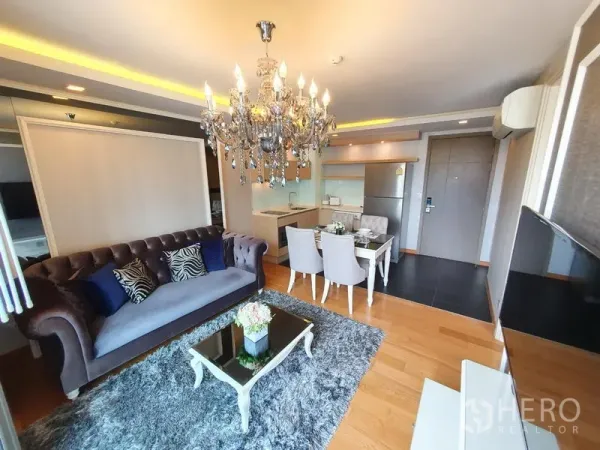 公寓 出租在Watthana, Bangkok - 客厅角度：天鹅绒沙发、玻璃茶几与吊灯相连开放式厨房。