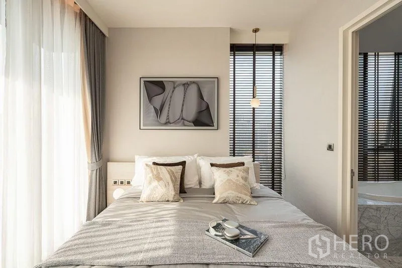 公寓 出租在Watthana, Bangkok - 主卧采光充足，转角窗与墙面装饰画，通往水疗风格套卫。