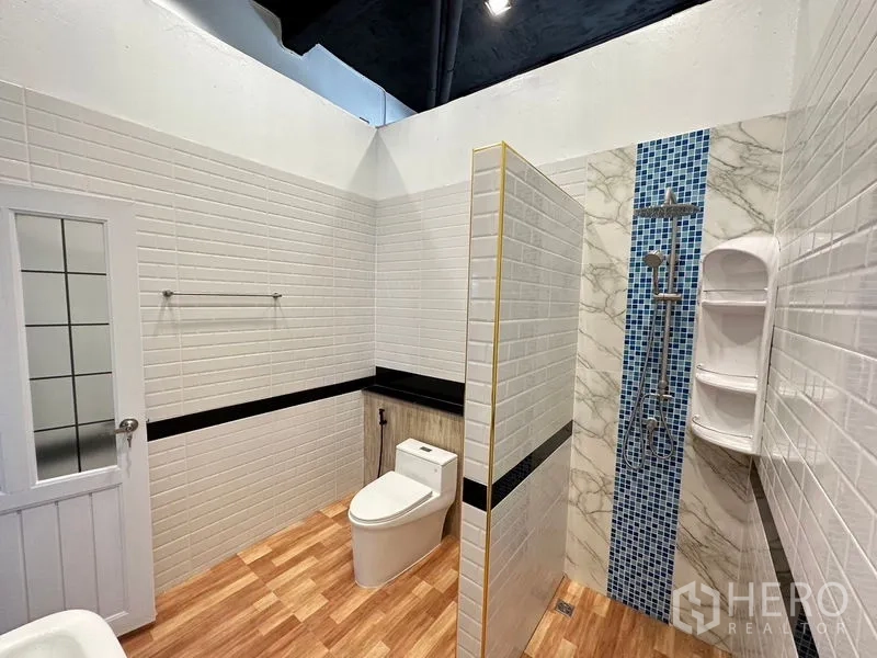 Office Space for rent in Bang Sao Thong, Samut Prakan - Renovated bathroom with toilet and shower, white subway tiles and wood-look floor.