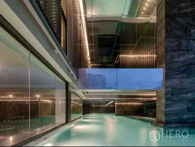 Condominium for rent in Khlong Toei, Bangkok - Covered lap pool with modern lighting and glass walls.