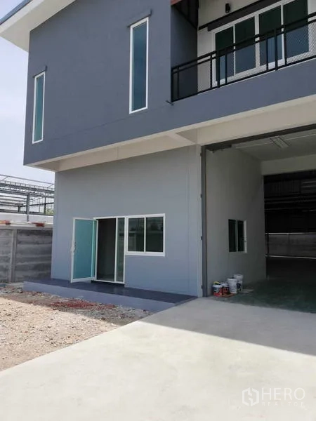 Warehouse for rent in Mueang Samut Sakhon, Samut Sakhon - Side view of the warehouse showing sliding glass door, windows and concrete loading area.