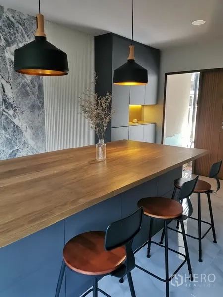 Townhouse for rent in Bang Phli, Samut Prakan - Stylish kitchen island with wood countertop, bar stools and matte cabinetry under pendant lamps.