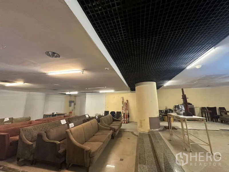 零售空间 出租 - 室内长排沙发，黑色格栅吊顶与中央立柱