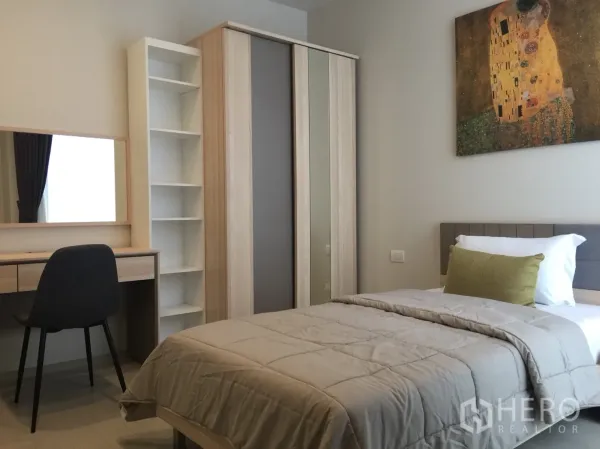 Condominium for rent in Pathum Wan, Bangkok - Second bedroom with single bed, study desk and mirror, open shelving, and sliding-door wardrobe.