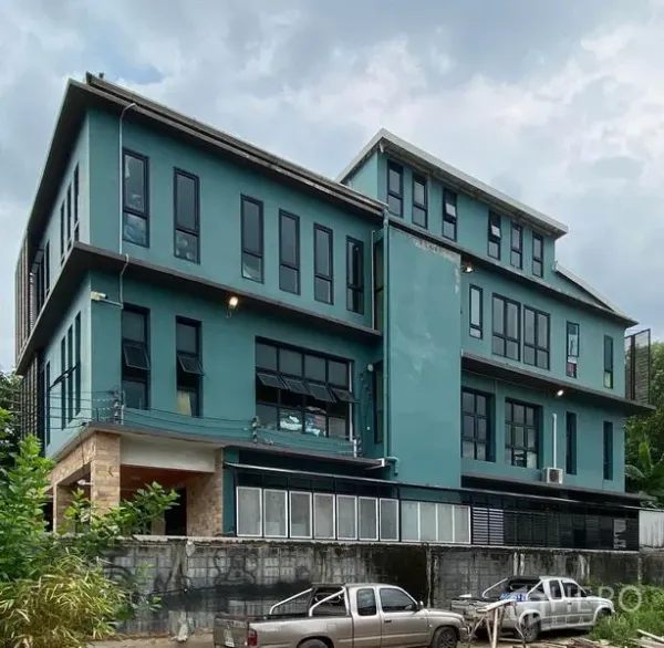 办公空间 出售在Lat Phrao, Bangkok - 办公楼侧立面，青绿色外墙与成排黑框窗户及阳台