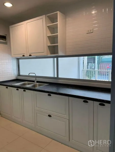ทาวน์เฮาส์ ให้เช่าในSuan Luang, Bangkok - ครัวสว่าง ตู้ทรงเชคเกอร์สีขาว ผนังกระเบื้องซับเวย์ ท็อปสีดำยาว และอ่างล้างจานคู่ใตหน้าต่างบานยาว