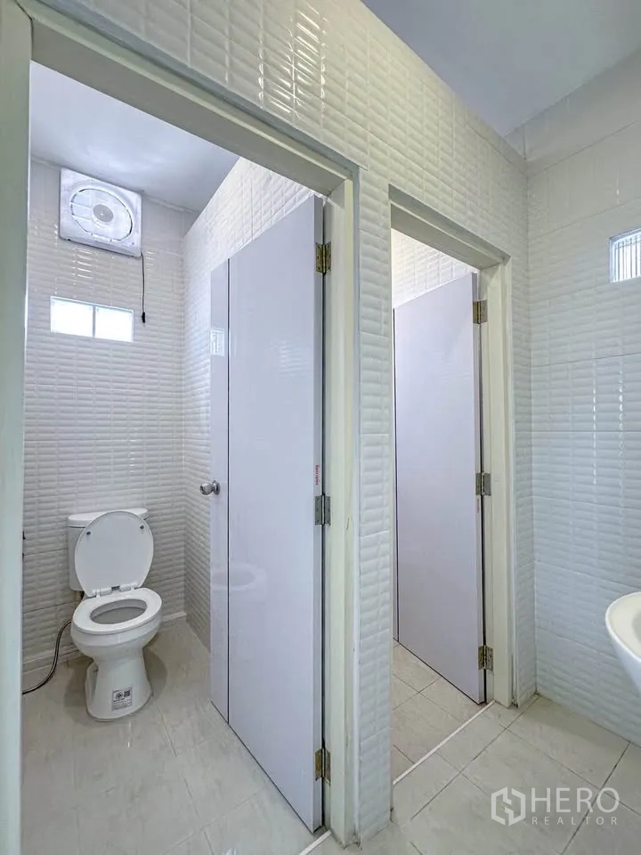 联排别墅 for sale in Wang Thonglang, Bangkok - 白色瓷砖卫生间，配坐便器与排风扇。