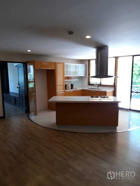 Condominium for sale - Kitchen with island and floor-to-ceiling windows opening to balcony.