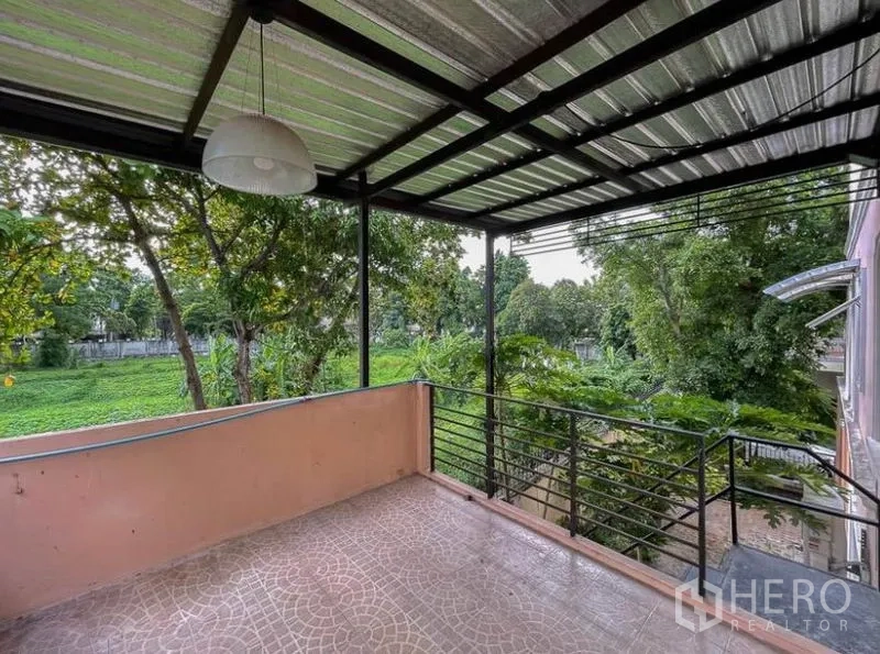 Townhouse for rent in Phasi Charoen, Bangkok - Covered rear balcony with metal roof and open greenery views.