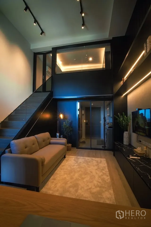 คอนโด for rent in Huai Khwang, Bangkok - ห้องนั่งเล่นดูเพล็กซ์เพดานสูง พร้อมบันได โซฟา ผนังกระจก และชั้นวางทีวี