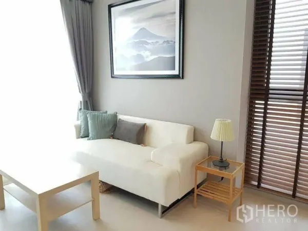 คอนโด ให้เช่าหรือขายในKhlong Toei, Bangkok - มุมนั่งเล่นอบอุ่น โซฟาสีขาว โคมไฟข้างโซฟา และบานหน้าต่างสูงแบบบังตา