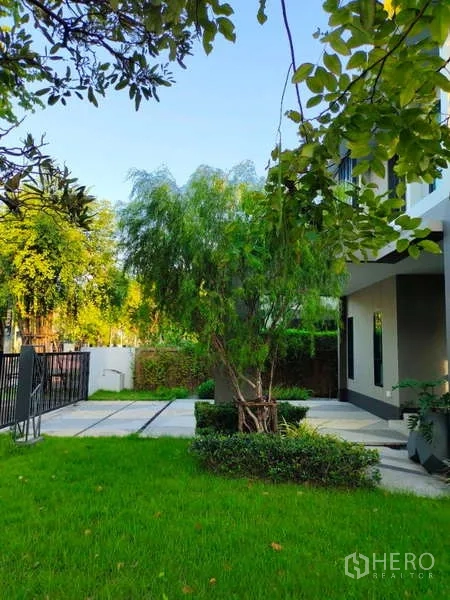 Detached House for rent in Bang Phli, Samut Prakan - Green side garden with trees, hedges and paved driveway at the gate.