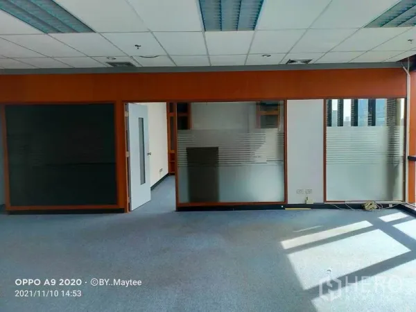 办公空间 出租在Watthana, Bangkok - Asok 站附近的开放式办公室，磨砂玻璃隔间、木质边框、蓝色地毯与吊顶灯光。