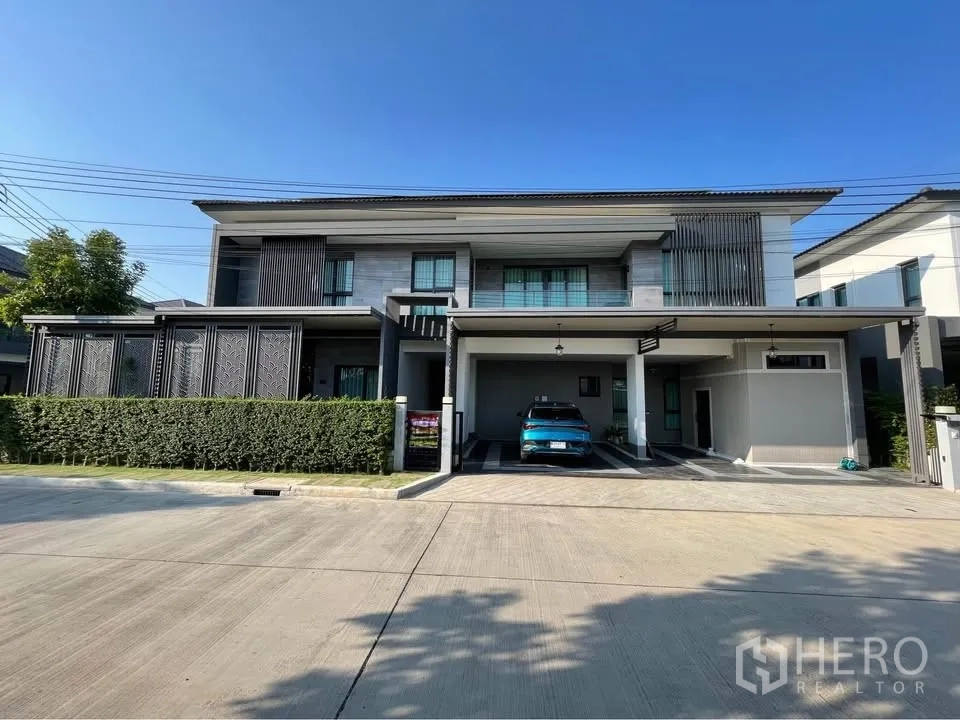 บ้านเดี่ยว for rent or sale in Bang Phli, Samut Prakan - บ้านเดี่ยวสองชั้นสไตล์โมเดิร์น ด้านหน้ามีพุ่มไม้และโรงจอดรถในร่มกว้าง