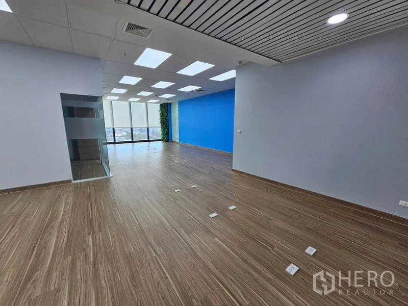 Office Space for rent in Sathon, Bangkok - Open workspace with blue feature wall and a vertical green wall by panoramic windows.