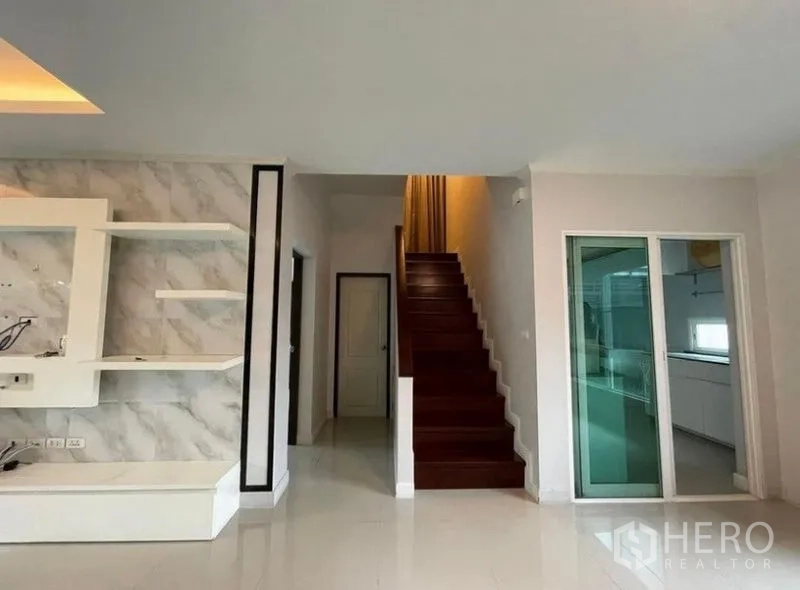 独立式住宅 出售在Bang Phli, Samut Prakan - 木楼梯，旁有推拉门通往独立厨房与走廊。