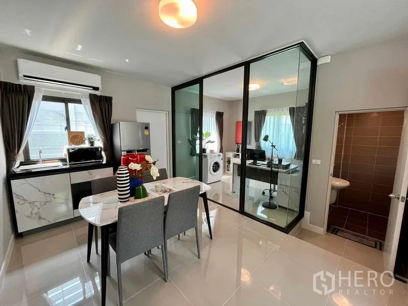 Townhouse for sale in Sai Mai, Bangkok - Kitchen and dining with marble-look cabinets, glass office, and a ground-floor bathroom.
