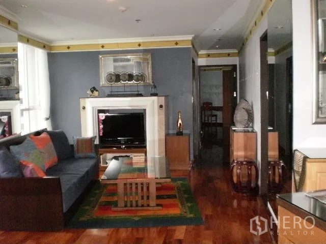 Condominium for rent in Pathum Wan, Bangkok - Cozy living room with sofa, TV console and decorative fireplace on glossy wooden flooring.