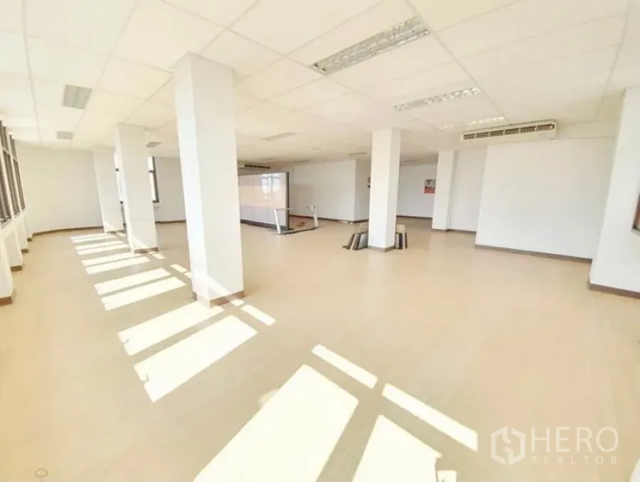 Office Space for rent in Bang Na, Bangkok - Sunlit open-plan office floor in Bang Na with pillars, large windows, wood-look flooring and ceiling lights.