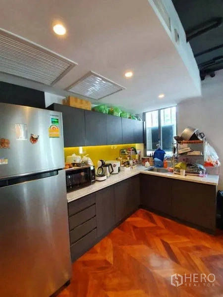 Office Space for rent in Khlong Toei, Bangkok - Pantry kitchen with L-shaped cabinetry, stainless refrigerator and countertop appliances.