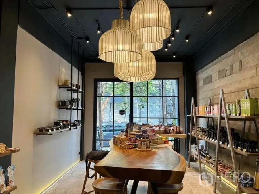 Retail Space for rent in Bang Rak, Bangkok - Boutique store view with oversized pendant lamps, central live-edge counter, stools and street-facing windows.
