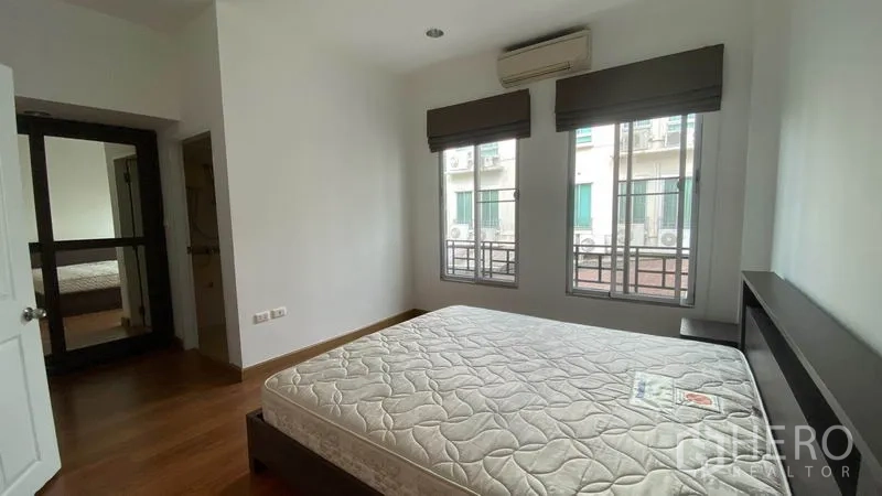 Townhouse for rent in Wang Thonglang, Bangkok - Sunlit bedroom with double bed, air conditioner, and two windows.