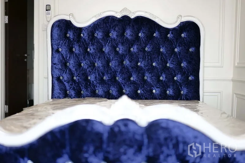 คอนโด ให้เช่าในKhlong Toei, Bangkok - ภาพระยะใกล้หัวเตียงกำมะหยี่สีน้ำเงินปักกระดุมกรอส พร้อมกรอบสีขาว