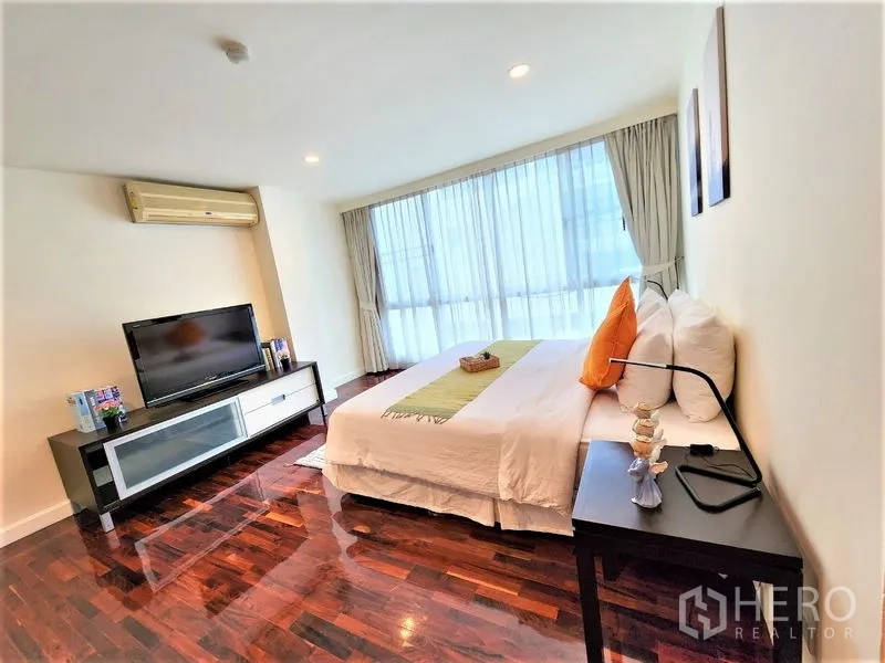 Condominium for rent in Bang Rak, Bangkok - Light-filled bedroom with king bed, bedside tables, TV bench and curtain-walled windows.