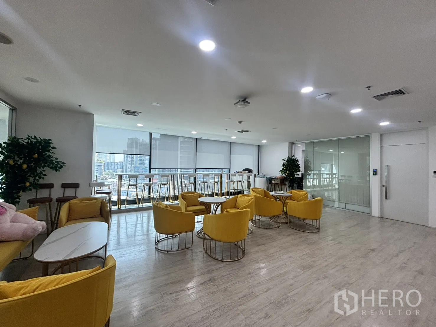 办公空间 for rent in Din Daeng, Bangkok - 员工休息区，黄色单椅，窗边吧台座位与城市景观。