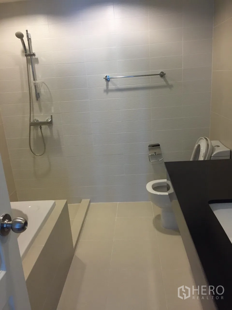 Condominium for rent in Huai Khwang, Bangkok - Contemporary bathroom with bathtub, handheld shower, toilet and long vanity counter.