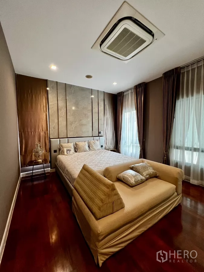 Detached House for rent or sale in Prawet, Bangkok - Cozy bedroom with padded headboard, corner windows and upholstered bench.