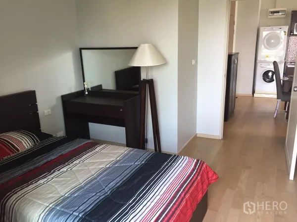 คอนโด ให้เช่าในWatthana, Bangkok - ห้องนอนที่สอง ปูผ้าปูที่นอนลายทาง โต๊ะเครื่องแป้ง พื้นไม้ มองเห็นทางไปครัวและชุดซักอบ