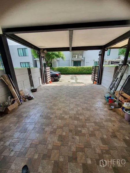 Townhouse for sale in Khlong Toei, Bangkok - Covered carport with tiled floor and sliding gate at a modern townhouse in Phra Khanong.