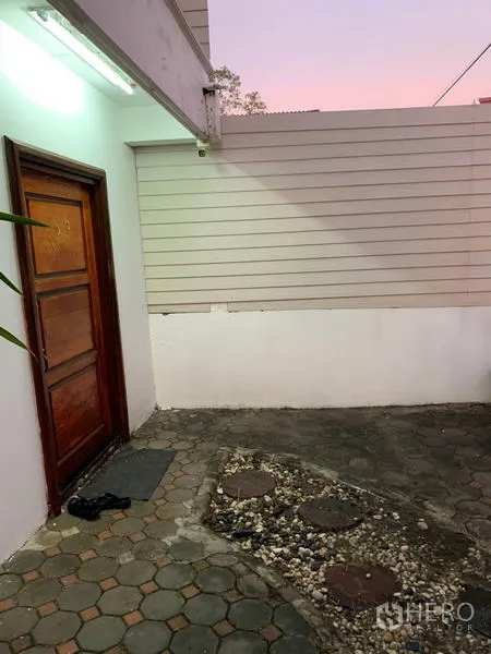 ทาวน์เฮาส์ ให้เช่าหรือขายในPhra Khanong, Bangkok - ลานหน้าบ้านปูบล็อกหกเหลี่ยม กำแพงสีขาว และประตูไม้ยามเย็น