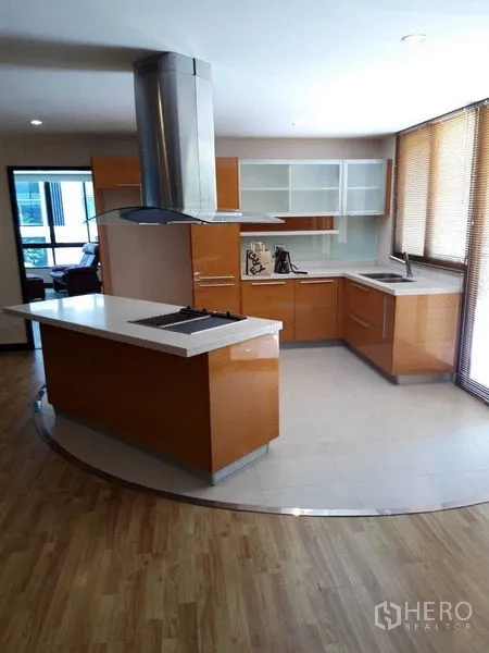 Condominium for sale - Open-plan kitchen with island cooktop, range hood, and ample cabinets.