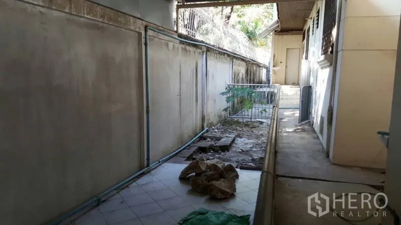Detached House for rent in Khlong Toei, Bangkok - Rear service corridor with tiled walkway, exposed plumbing and utility access.