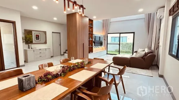Detached House for rent in Bang Phli, Samut Prakan - Eight‑seat wooden dining table beside the garden‑view living room.