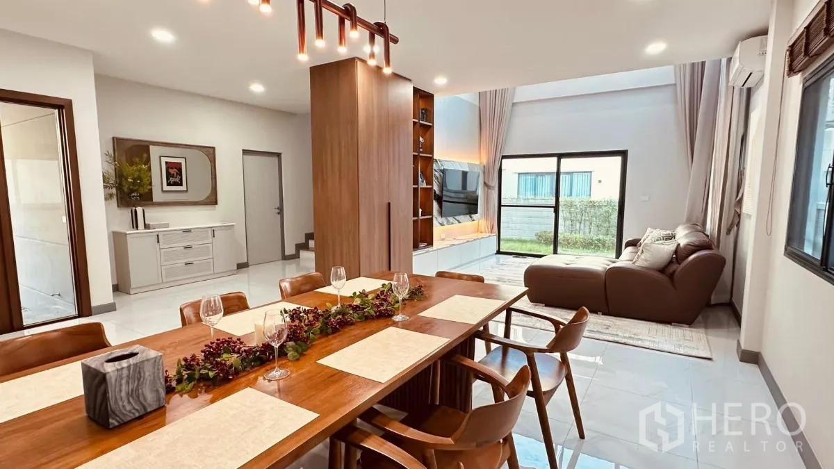 Detached House for rent in Bang Phli, Samut Prakan - Eight‑seat wooden dining table beside the garden‑view living room.