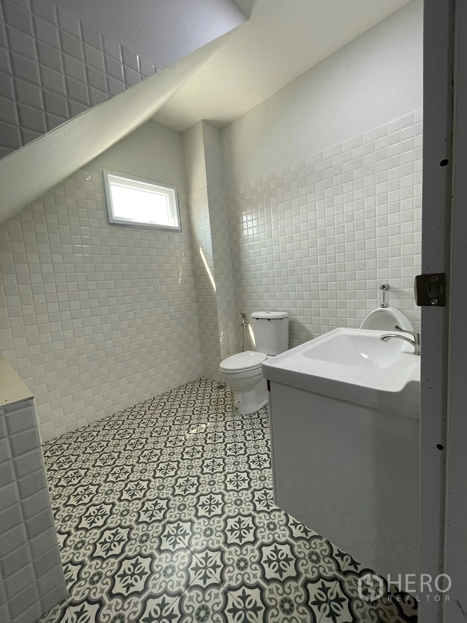 Factory for rent or sale in Bang Phli, Samut Prakan - Bathroom with patterned tiles, white vanity, toilet, and a small window.