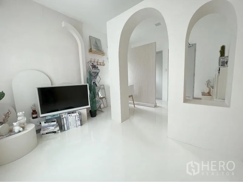 Detached House for rent or sale in Prawet, Bangkok - Bright white room with arched doorways, TV console and minimalist décor.