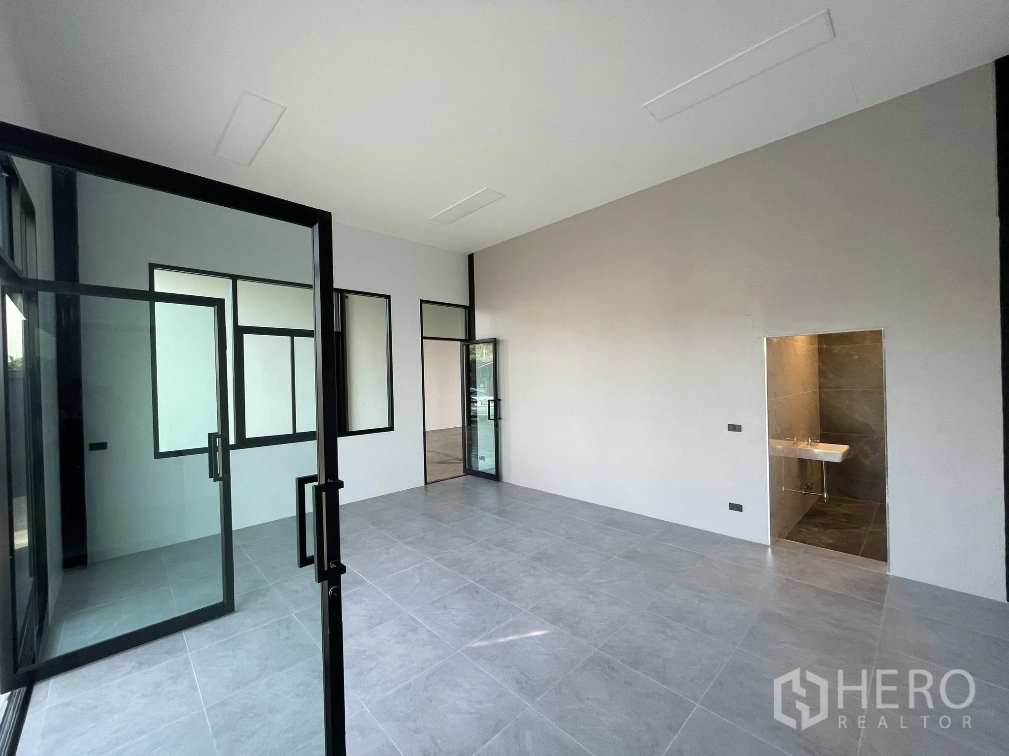 Warehouse for rent in Phra Samut Chedi, Samut Prakan - Glass-partitioned office room with attached restroom and tiled floor.