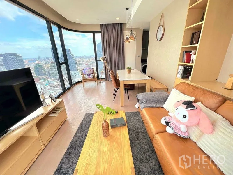 Condominium for rent in Bang Rak, Bangkok - Dining and living zone beside a curved glass wall with skyline backdrop.