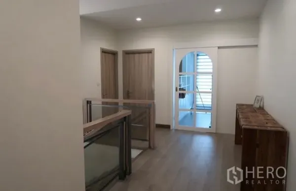 Detached House for rent or sale in Saphan Sung, Bangkok - Bright upstairs landing with wood floors, glass balustrade, and two doors.