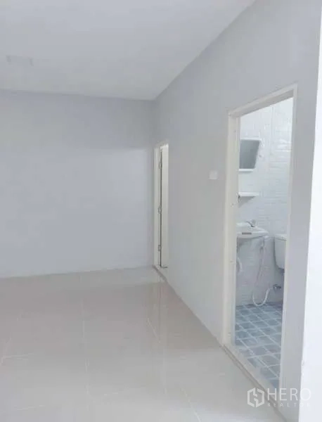 Warehouse for rent in Pathum Thani - Small corridor leading to a tiled restroom with sink and toilet inside the facility.