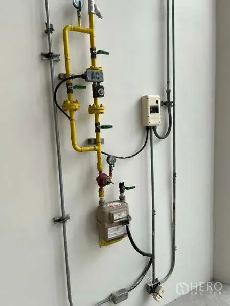 พื้นที่ขายปลีก ให้เช่าในPhaya Thai, Bangkok - ภาพระยะใกล้ของระบบสาธารณูปโภค แสดงท่อแก๊สสีเหลือง วาล์ว มิเตอร์ และตู้ควบคุมบนผนังสีขาว
