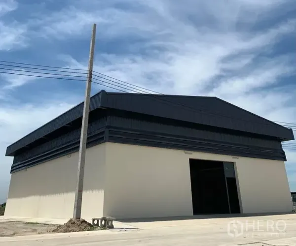 Warehouse for rent in Bang Bo, Samut Prakan - Corner view of modern warehouse building with wide loading apron under a blue sky.
