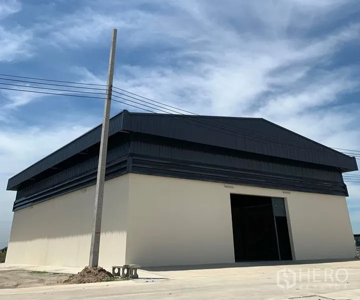 Warehouse for rent in Bang Bo, Samut Prakan - Corner view of modern warehouse building with wide loading apron under a blue sky.