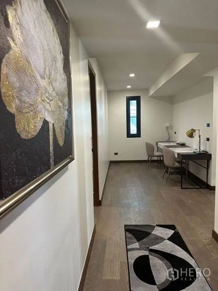 Detached House for rent in Suan Luang, Bangkok - Bright hallway with study desk, artwork and wood floor.
