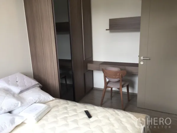 Condominium for rent in Watthana, Bangkok - Second bedroom featuring a fitted wardrobe and long work desk with shelving.
