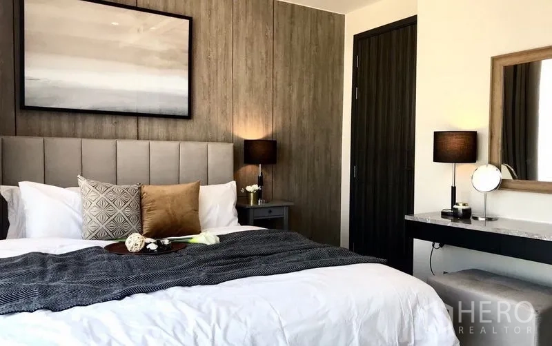 คอนโด ให้เช่าในWatthana, Bangkok - ห้องนอนใหญ่พร้อมหัวเตียงบุผ้า ผนังลายไม้ และโคมไฟข้างเตียง